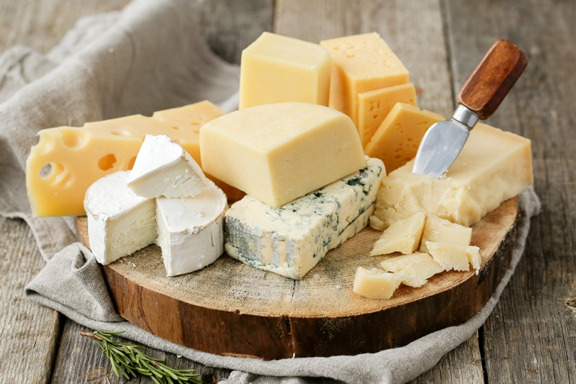A delicious assortment of cheeses on a rustic wooden board.